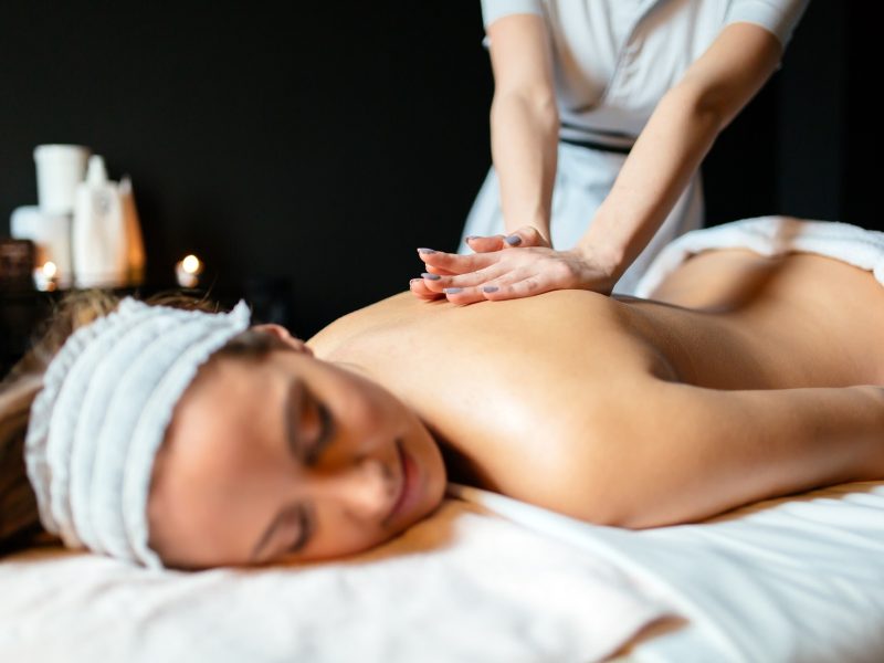Massage therapist massaging beautiful brunette in a spa